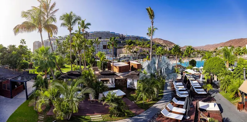 Vue aérienne d'un complexe hôtelier tropical avec piscine et palmiers.