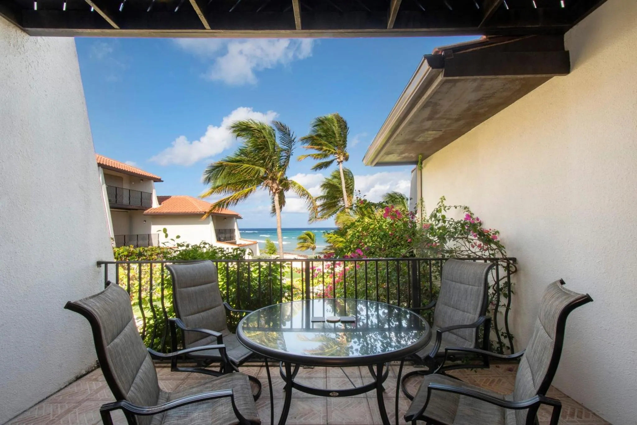 Une terrasse ombragée offre une vue sur la mer et la végétation tropicale.