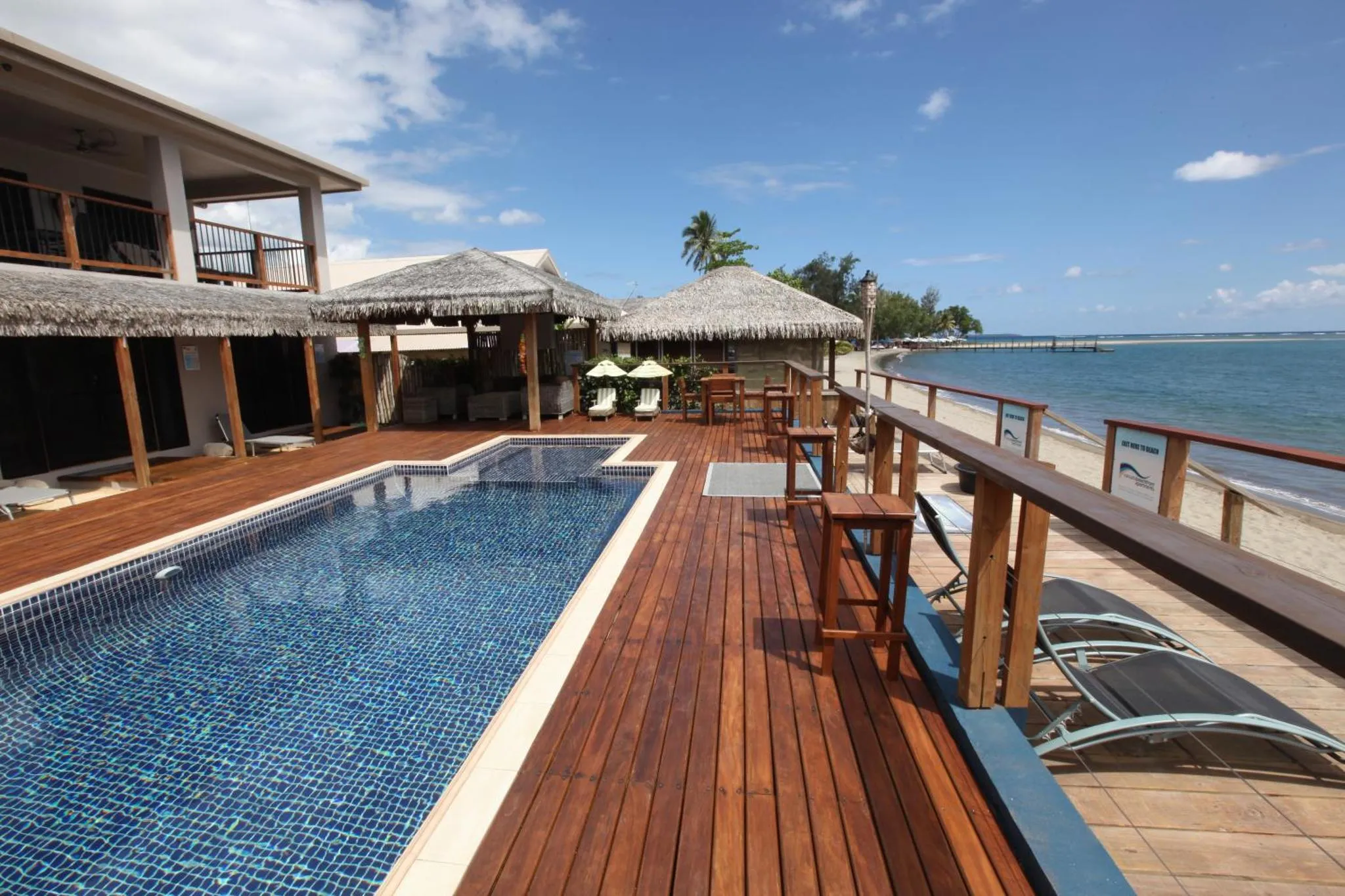Terrasse en bois avec piscine et mobilier de détente face à la mer.