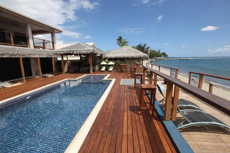 Terrasse en bois avec piscine et mobilier de détente face à la mer.