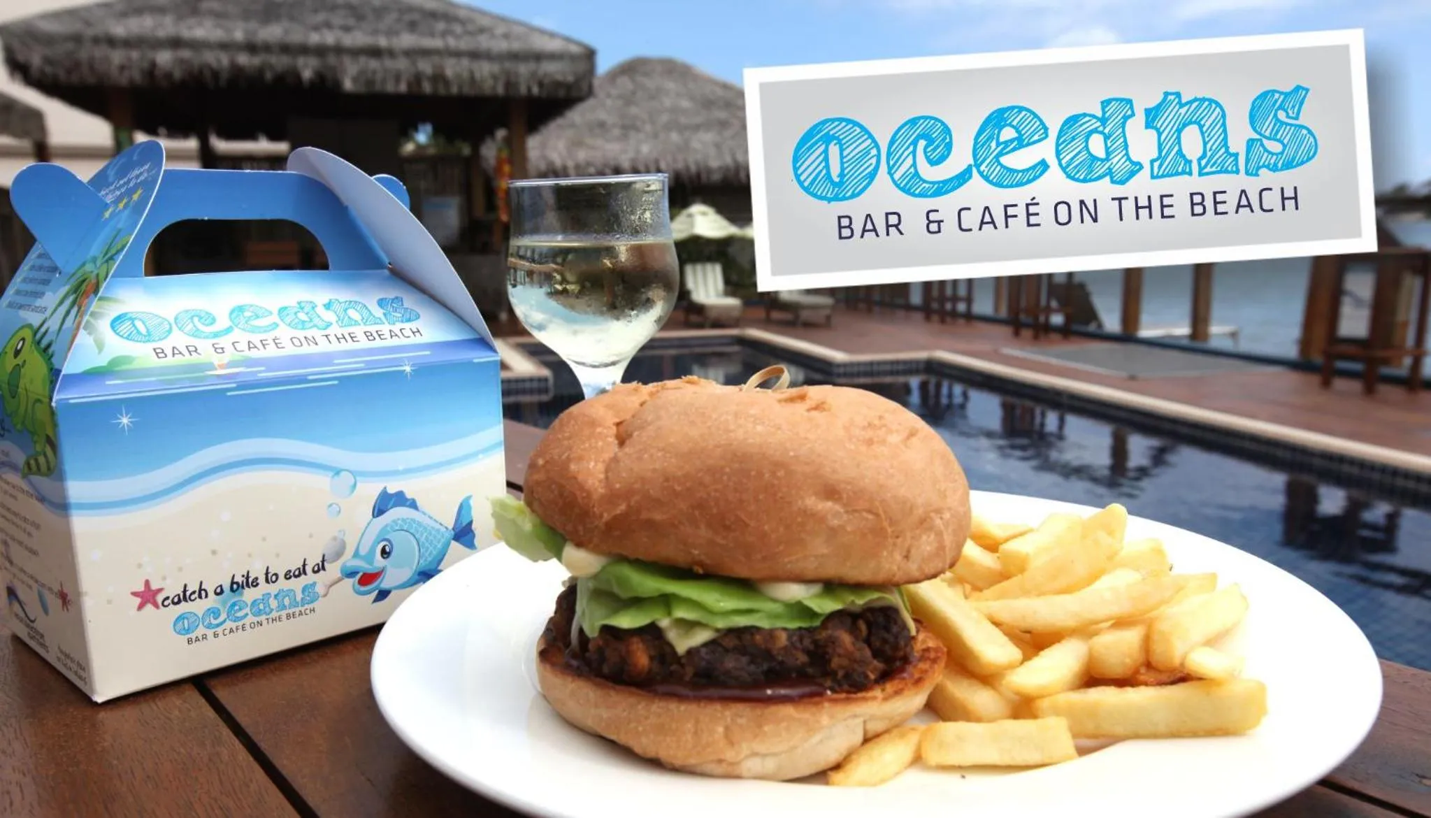 Un hamburger avec des frites et une boisson servis sur une table en extérieur.