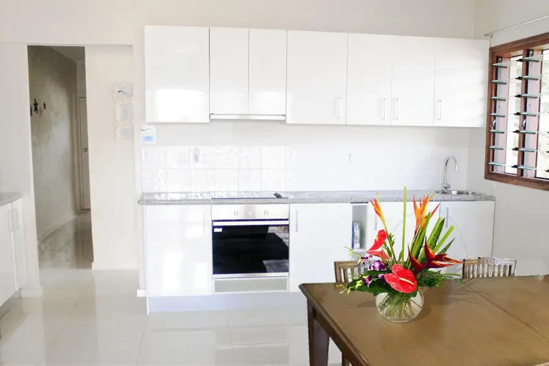 Cuisine lumineuse avec plan de travail et bouquet de fleurs.