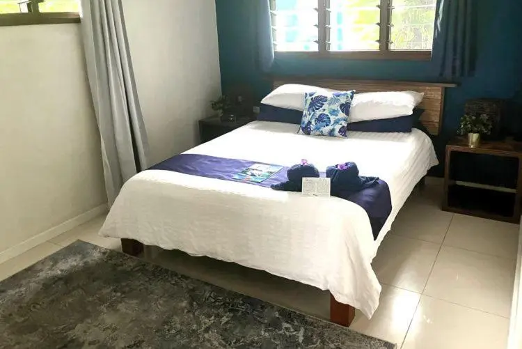 Une chambre lumineuse avec un lit double recouvert d'une courtepointe blanche et bleue.