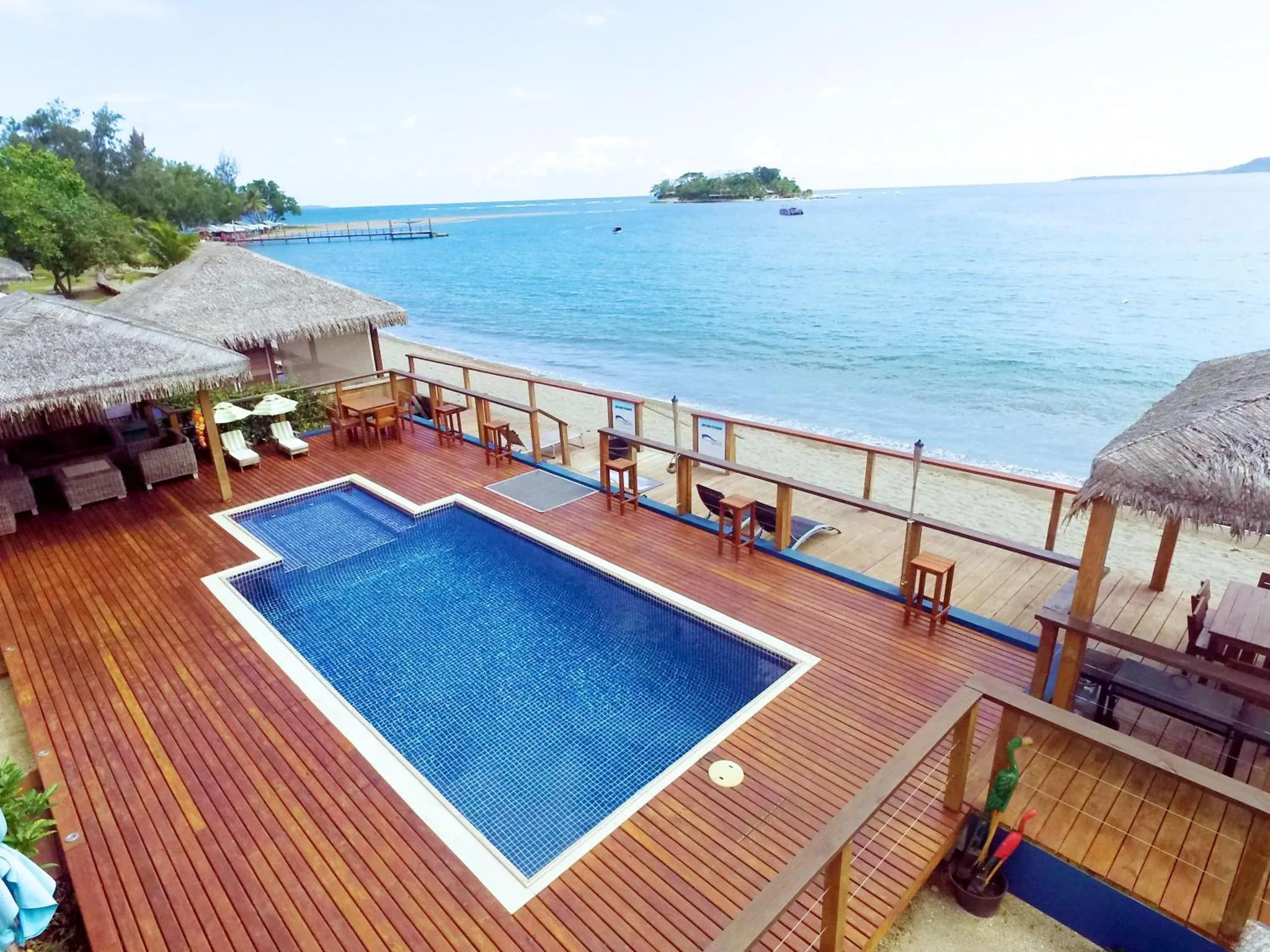 Terrasse en bois avec piscine et mobilier de détente face à la mer.