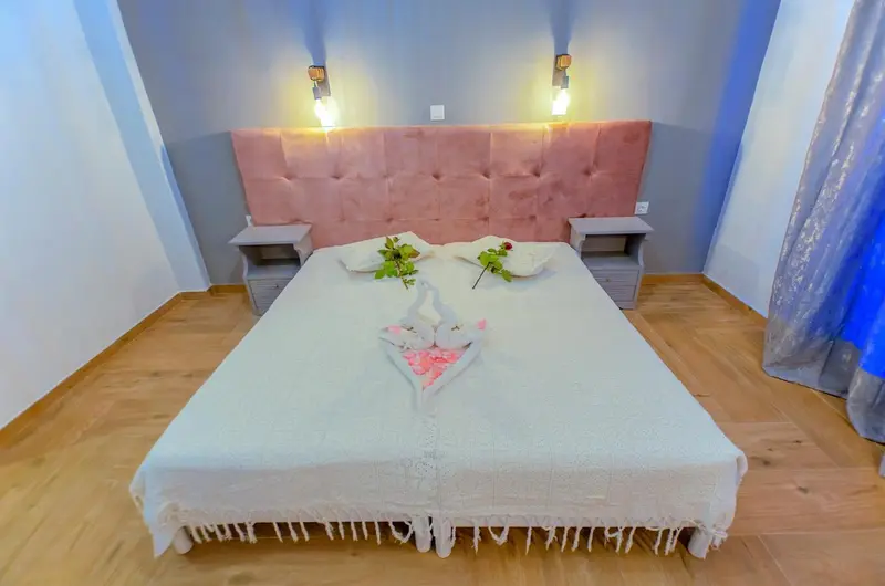 Une chambre avec un grand lit recouvert d'une courtepointe blanche et de roses.