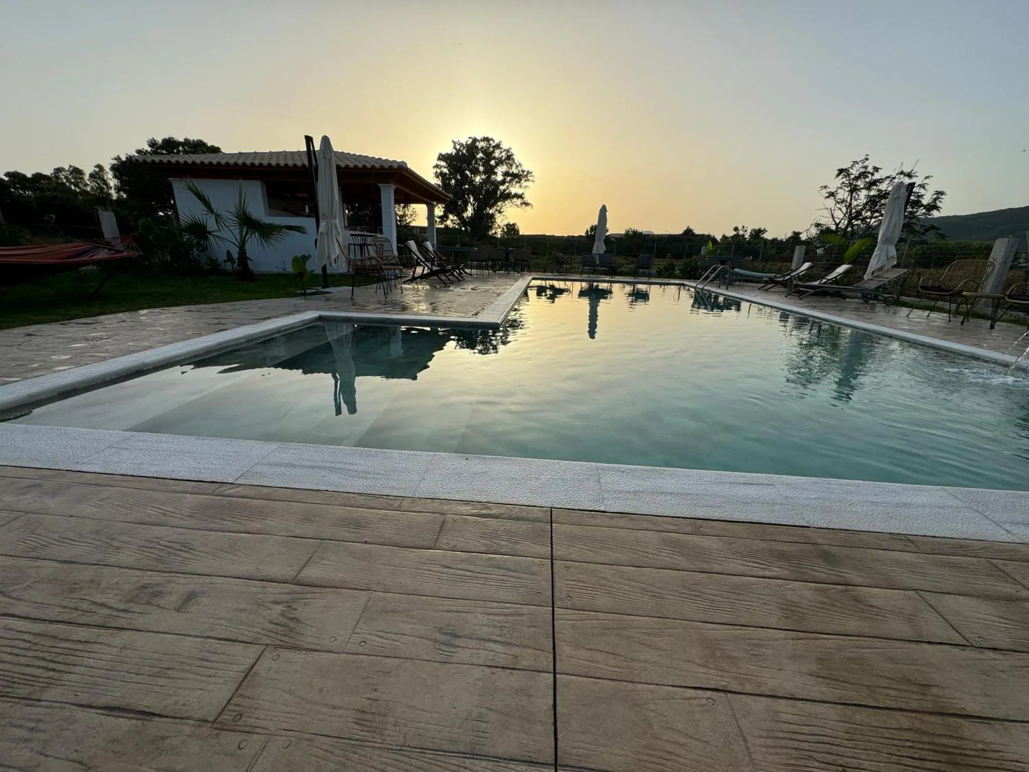 Une piscine rectangulaire avec une terrasse ensoleillée et des transats.