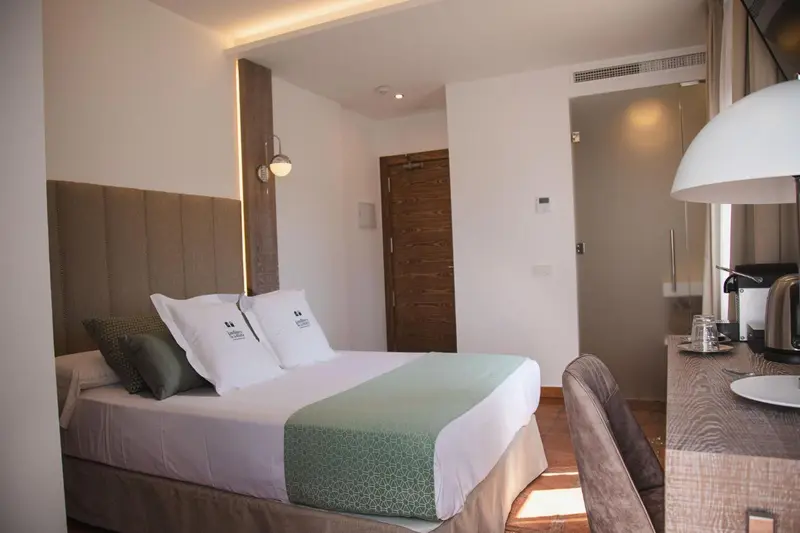 Une chambre lumineuse avec un grand lit et une table de chevet.