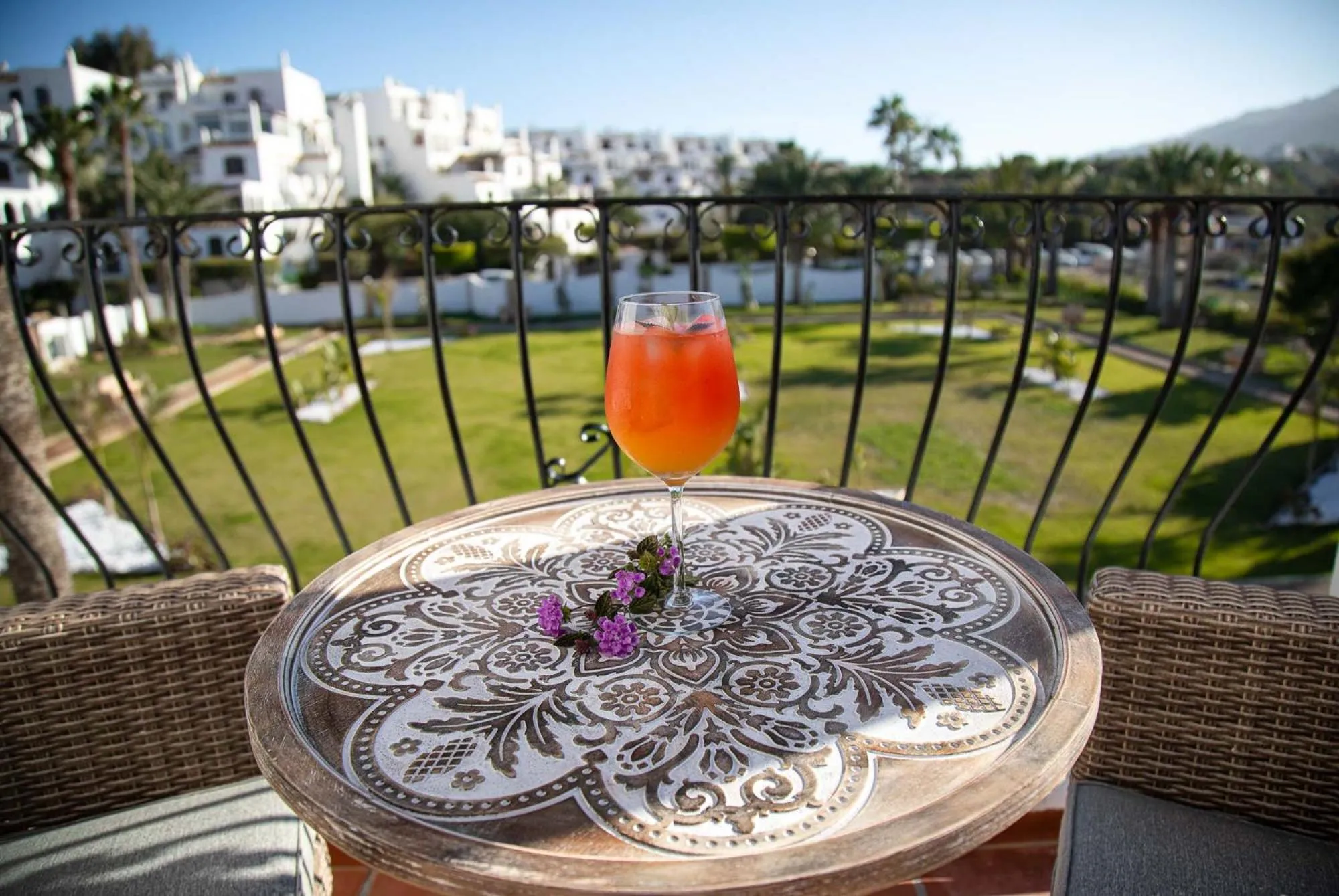 Une table ronde avec un cocktail est mise en scène sur une terrasse.