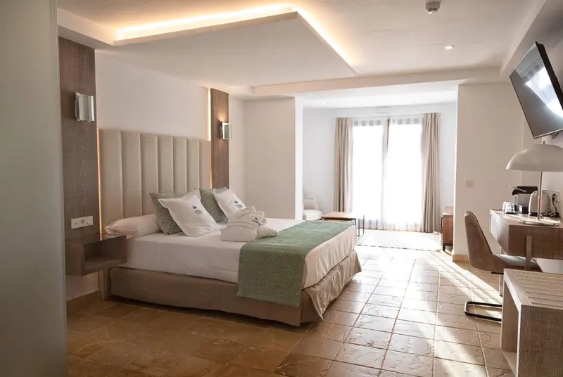 Une chambre lumineuse avec un grand lit et un bureau.