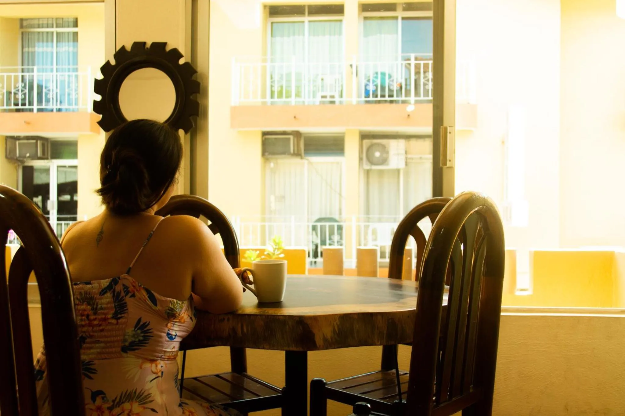Une personne est assise à une table en bois dans une salle lumineuse.