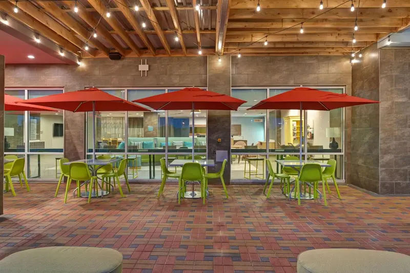 Terrasse ombragée avec tables et parasols rouges.