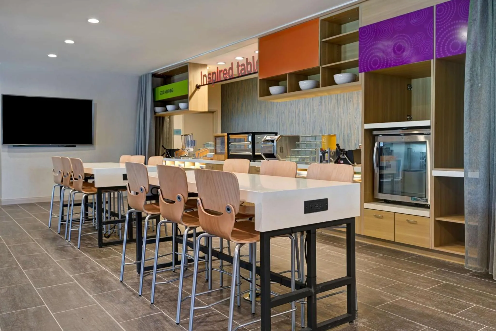 Une salle lumineuse avec un long comptoir de buffet et des tables à manger.