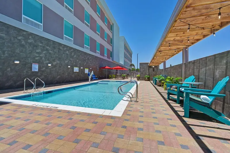 Une piscine turquoise entourée d'une terrasse pavée et de chaises longues bleues.