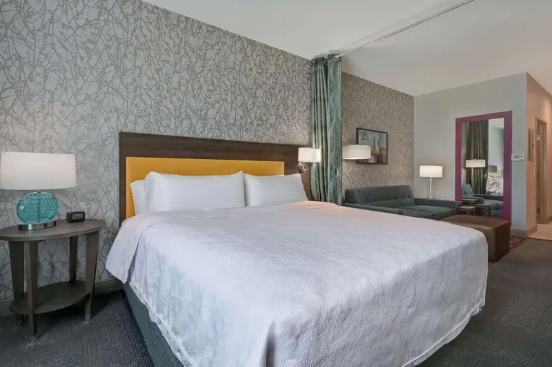 Une chambre d'hôtel avec un grand lit recouvert d'une couette blanche et de coussins.