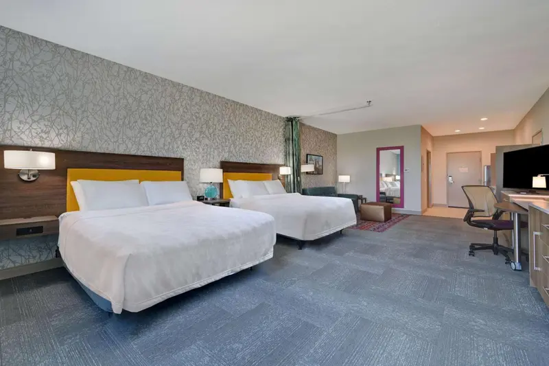 Une chambre d'hôtel lumineuse avec deux lits et un espace de travail.