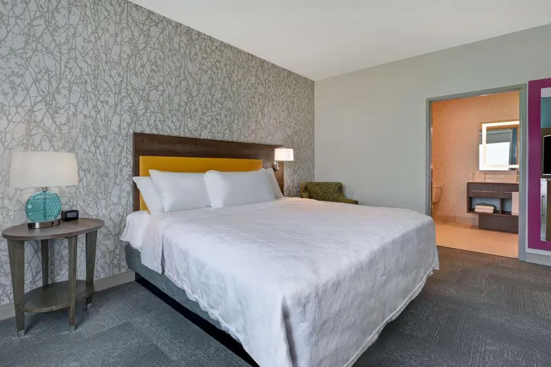 Une chambre d'hotel avec un grand lit blanc et une décoration murale texturée.