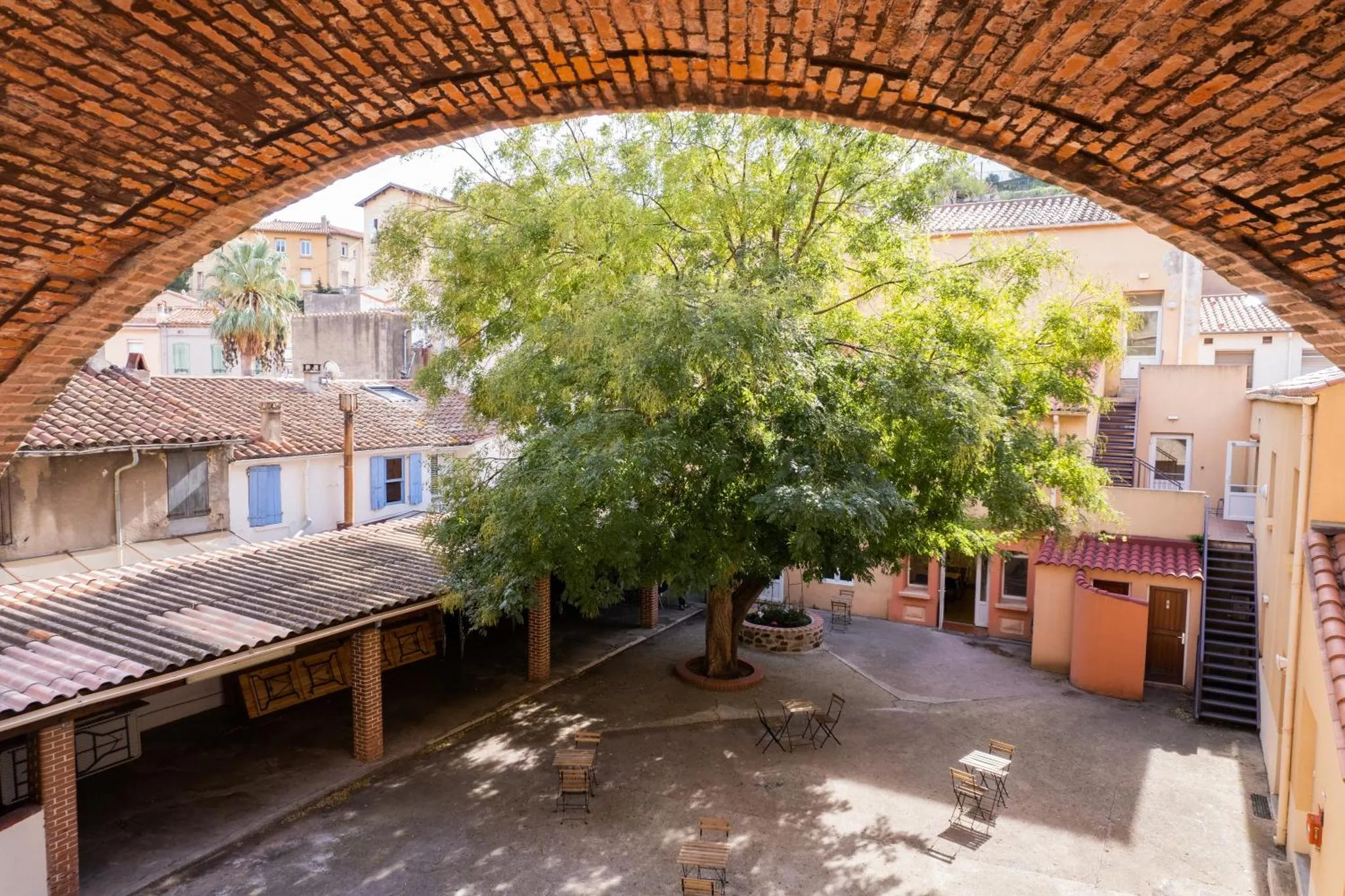 Une cour intérieure arborée avec des tables et des chaises.