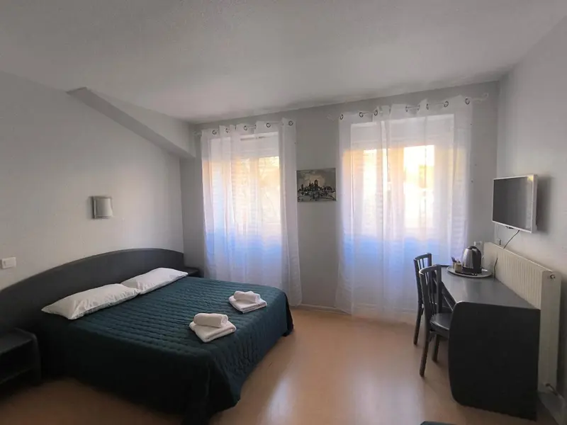 Une chambre lumineuse avec un lit double et un bureau.