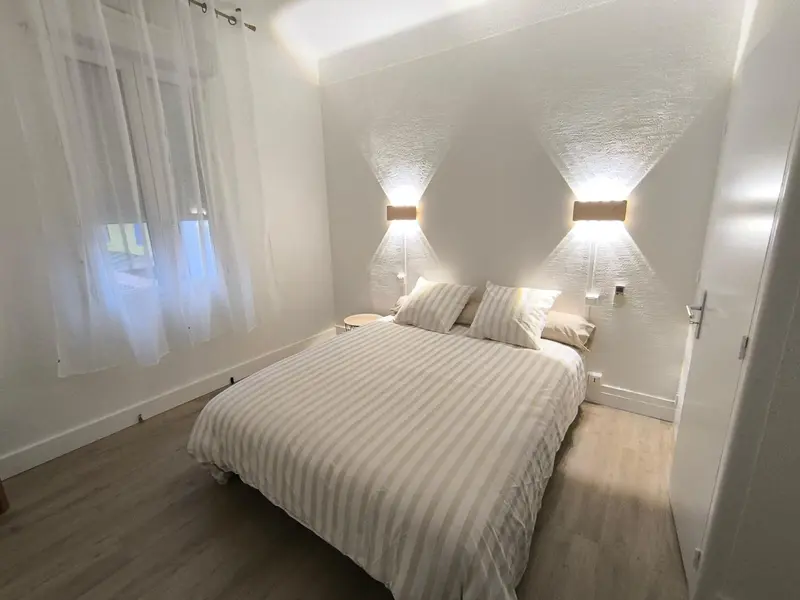 Une chambre lumineuse avec un grand lit recouvert d'une couette rayée.