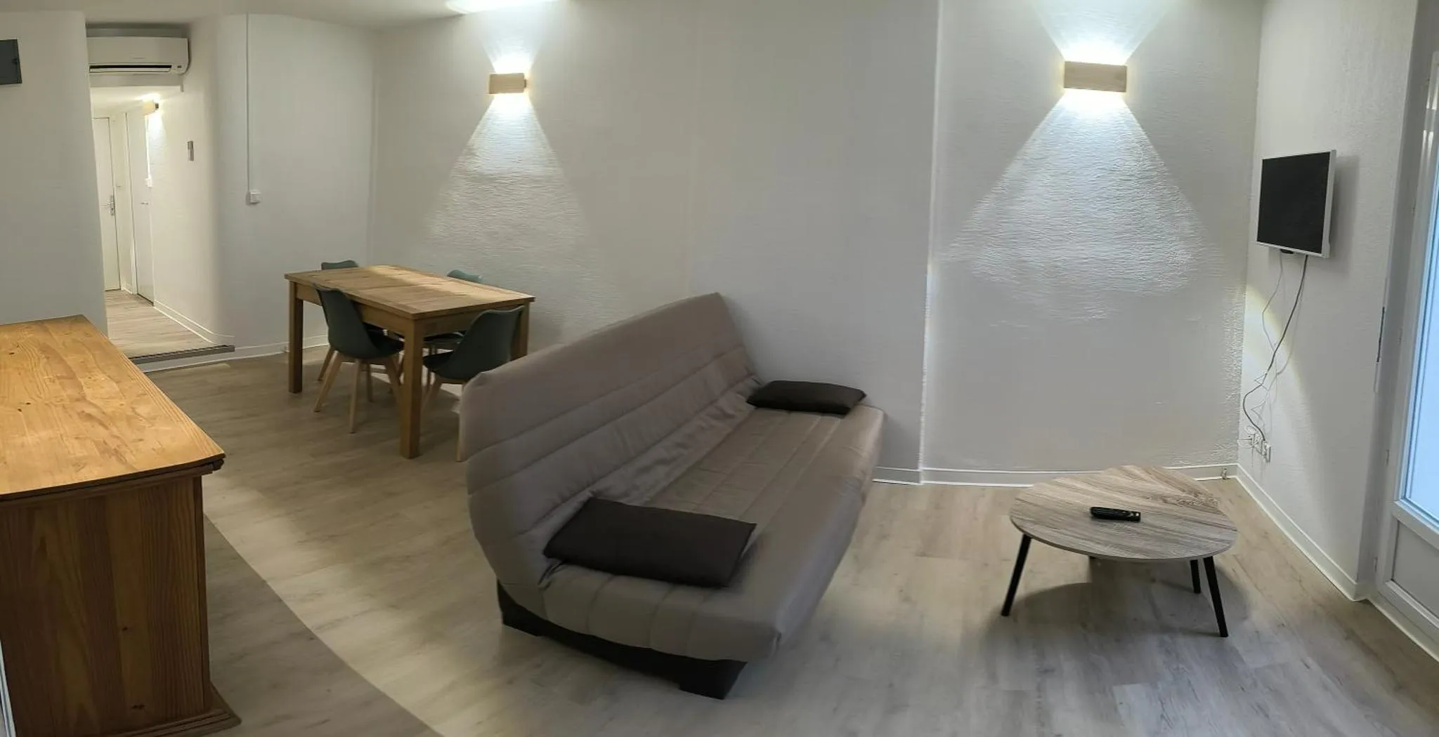 Espace de vie lumineux avec canapé, table et télévision.