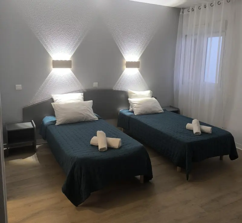 Une chambre avec deux lits simples et des couvertures bleues.