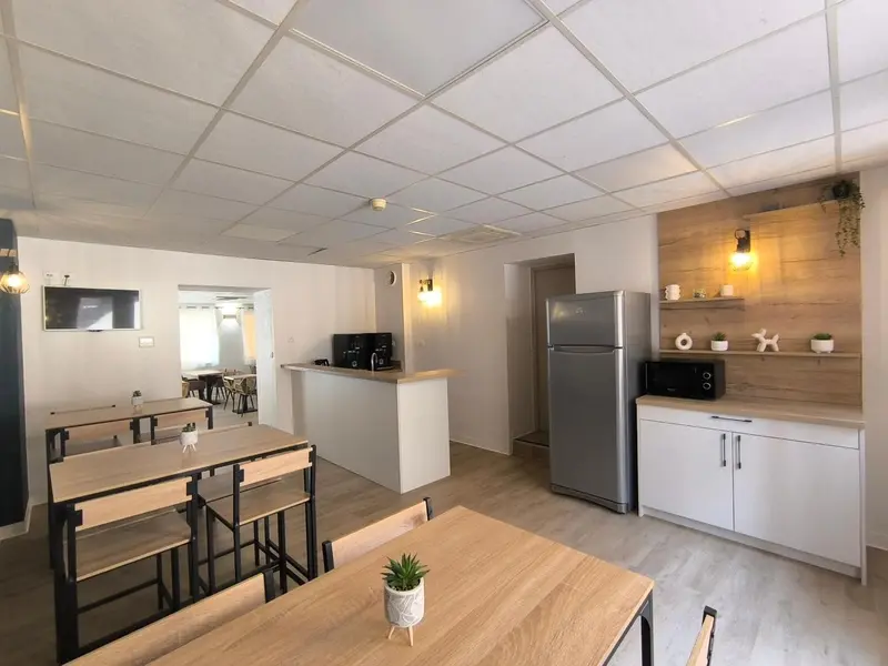 Une salle lumineuse avec des tables et un comptoir blanc.
