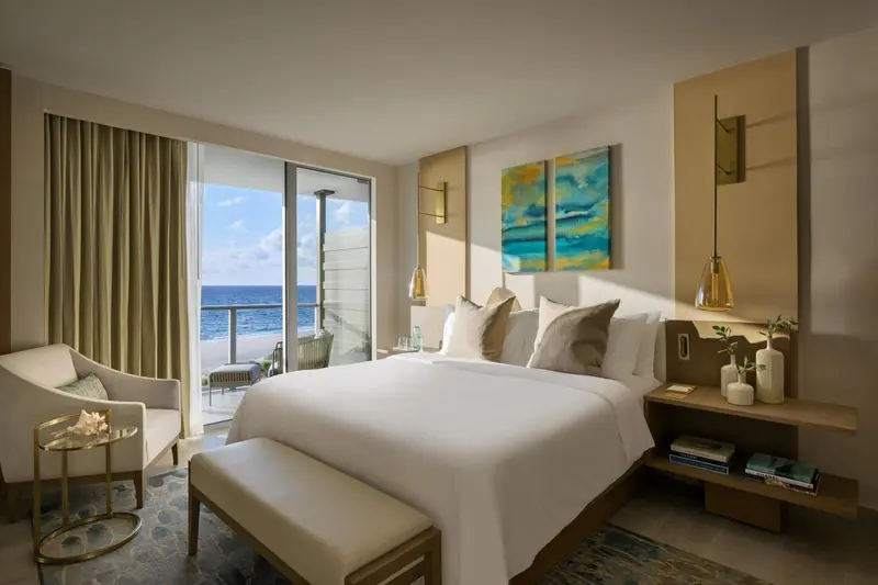 Chambre lumineuse avec un grand lit et vue sur la mer.