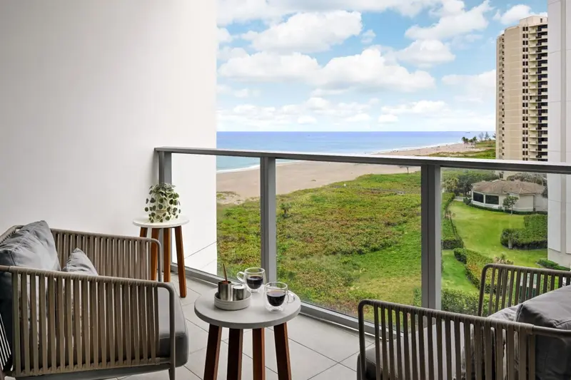 Vue d'un balcon avec mobilier d'extérieur donnant sur la mer et la plage.