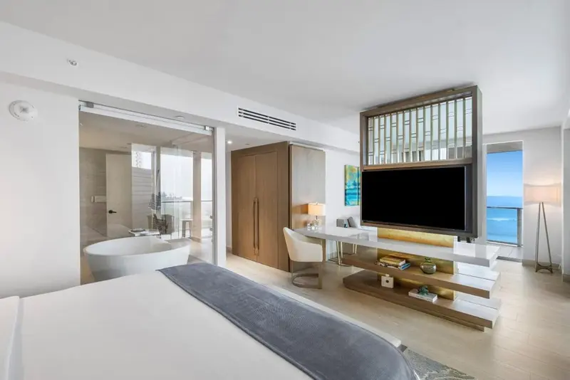 Chambre lumineuse avec baignoire et vue sur la mer.