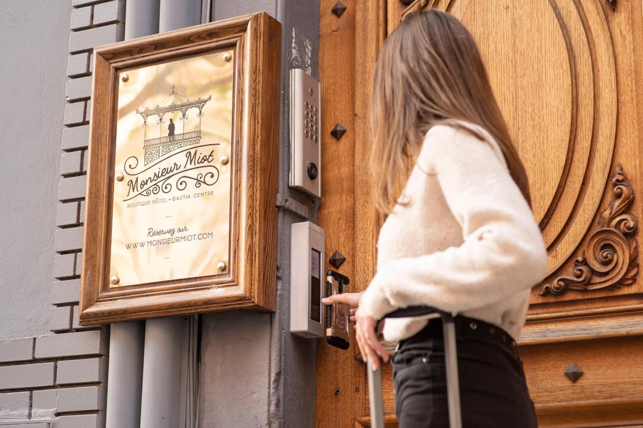 Une personne franchit le seuil d'un établissement avec une valise.