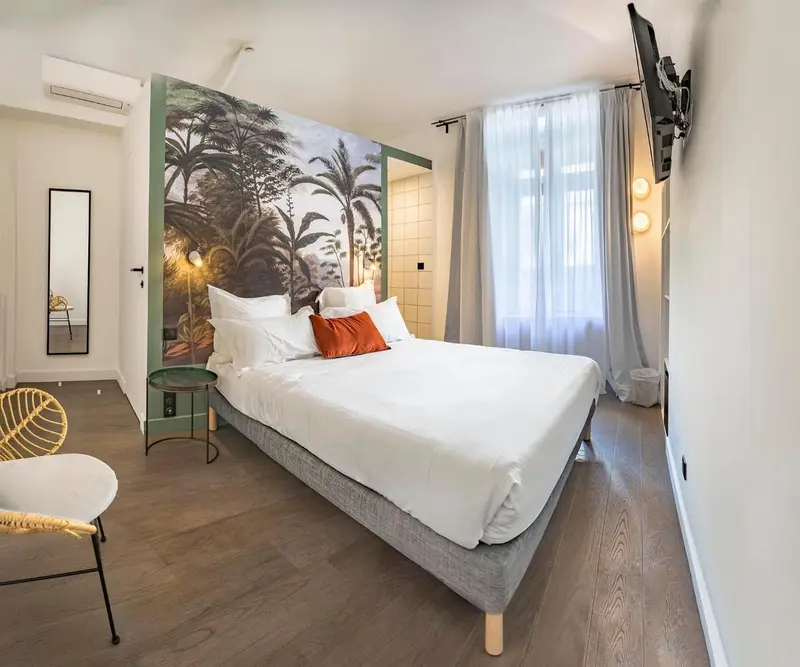 Une chambre lumineuse avec un grand lit et un mur décoré d'une forêt tropicale.