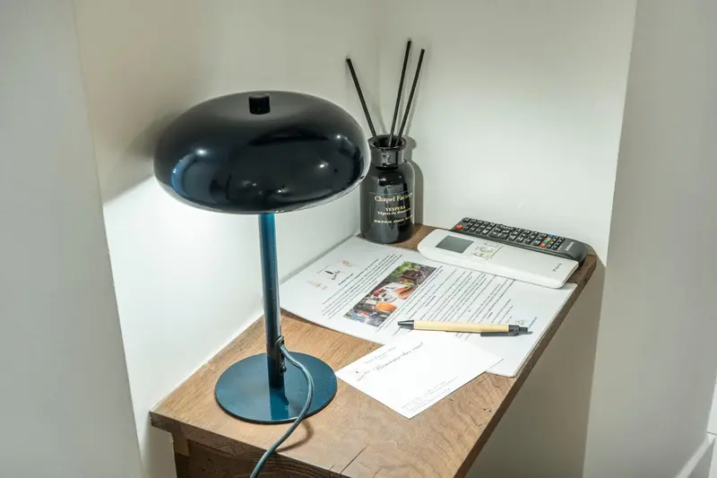 Une lampe de chevet et quelques objets posés sur une table en bois.