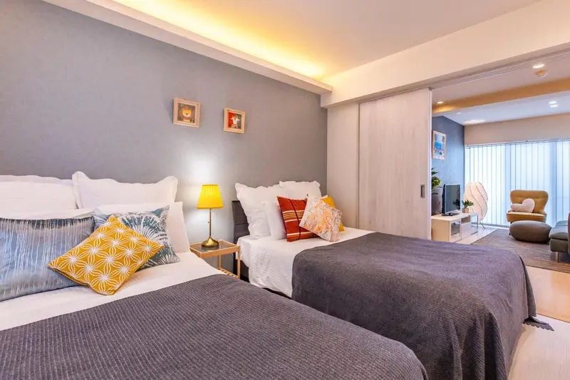 Une chambre lumineuse avec deux lits simples et un espace salon.