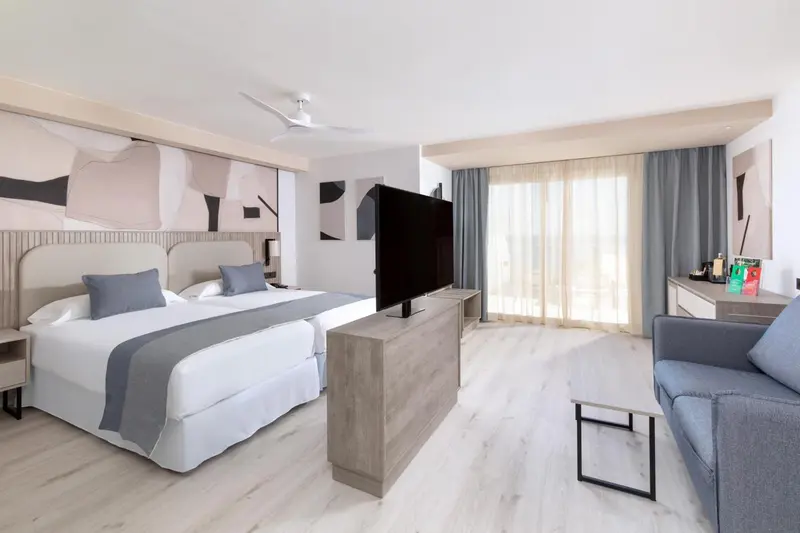 Chambre lumineuse avec un grand lit et un coin salon.
