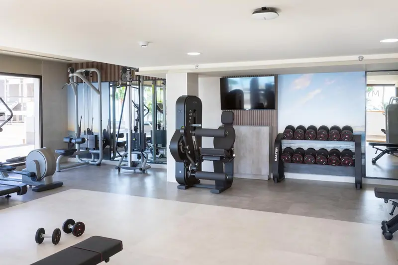 Une salle de sport lumineuse avec des équipements de musculation et des tapis.