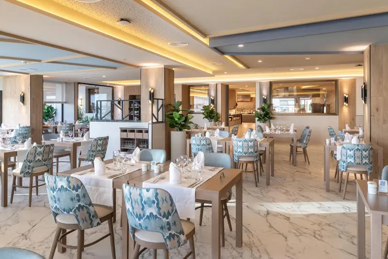 Une salle lumineuse avec des tables dressées pour un repas.