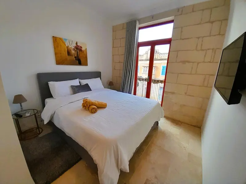 Une chambre lumineuse avec un grand lit et un accès à un balcon.
