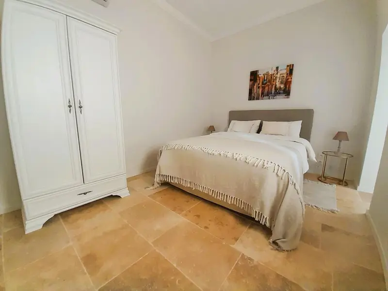 Une chambre lumineuse avec un grand lit et une armoire.