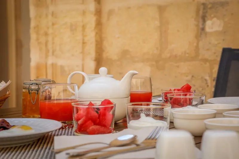 Une table est dressée avec une théière, des verres de jus et des fruits.