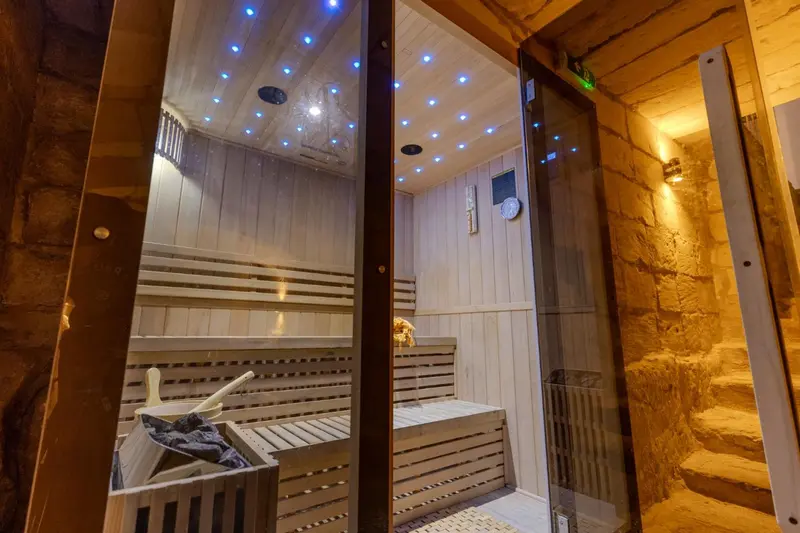 Intérieur d'un sauna en bois avec éclairage bleuté et murs en pierre.