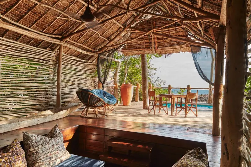 Espace de détente extérieur avec mobilier en bois et vue sur la mer.