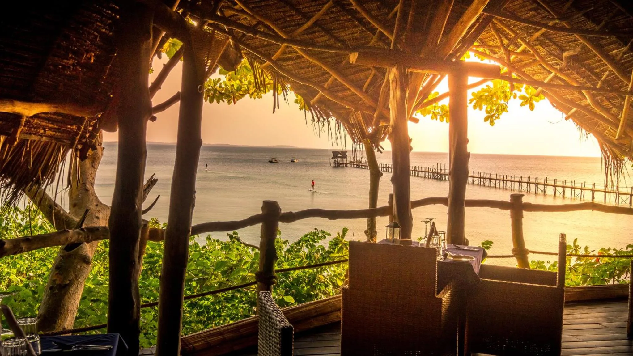 Une terrasse ombragée offre une vue sur la mer au coucher du soleil.