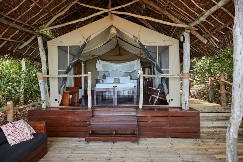 Une chambre avec un lit à baldaquin donnant sur une terrasse en bois.