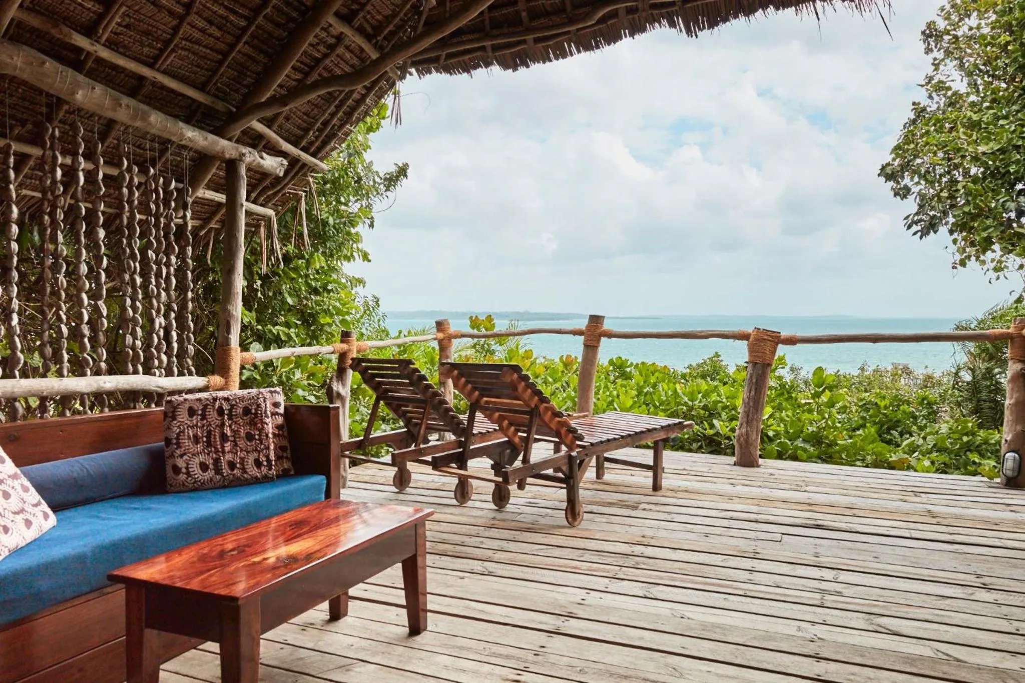 Terrasse en bois avec mobilier de détente face à la mer.
