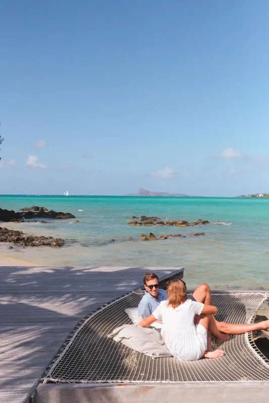 Un couple se détend dans un hamac au bord d'une plage turquoise.
