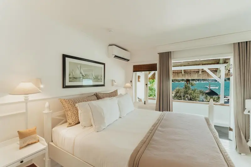 Une chambre lumineuse avec un grand lit et vue sur la mer.