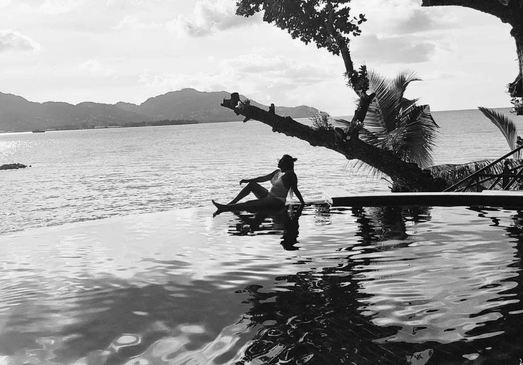 Une personne se détend au bord d'une piscine à débordement avec vue sur la mer.