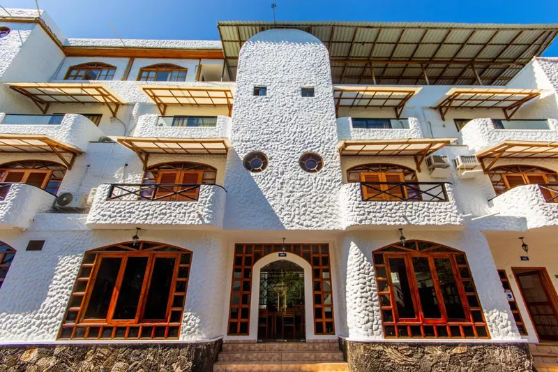 Façade blanche d'un bâtiment avec des ouvertures orange et des balcons.
