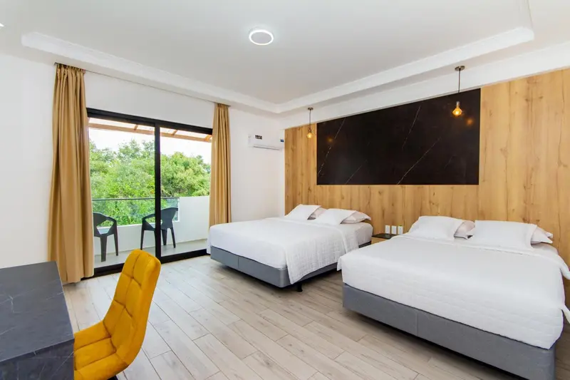 Chambre lumineuse avec deux lits et balcon.