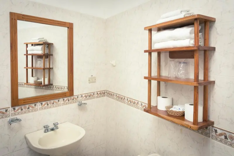 Une salle de bain claire avec un lavabo et des étagères en bois.